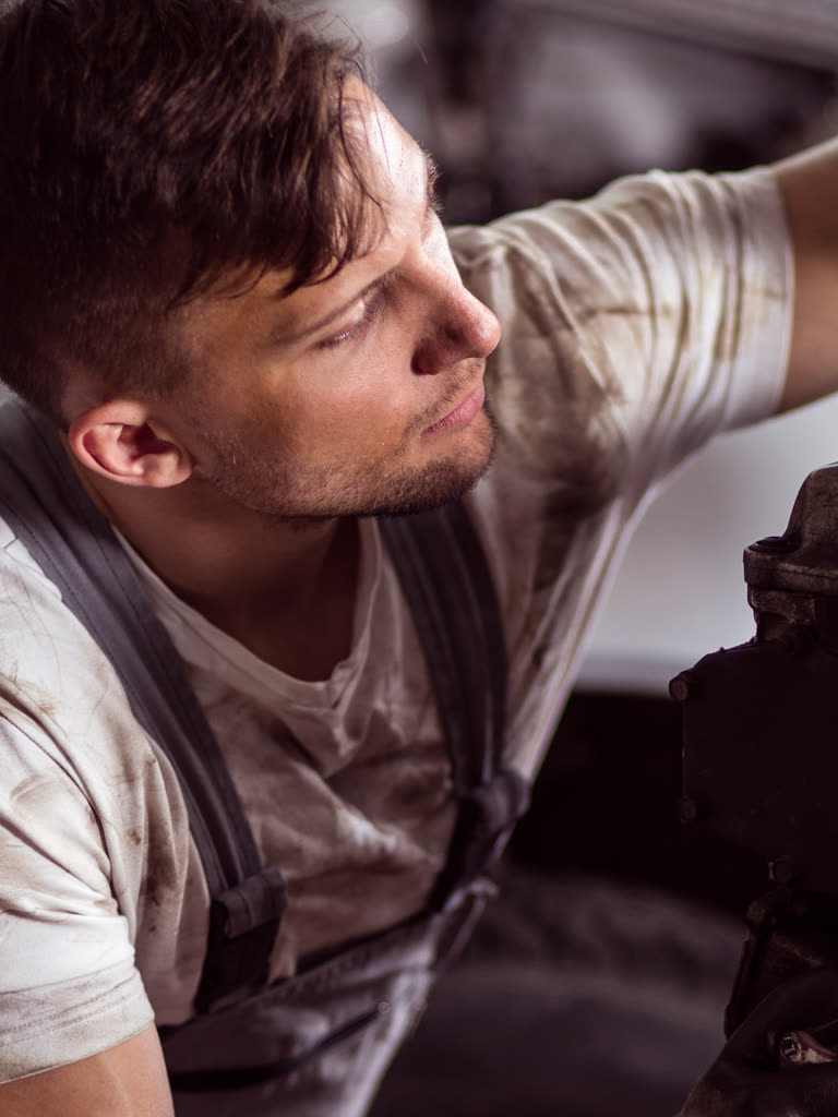 Technician working under a vehicle on a lift in a service bay