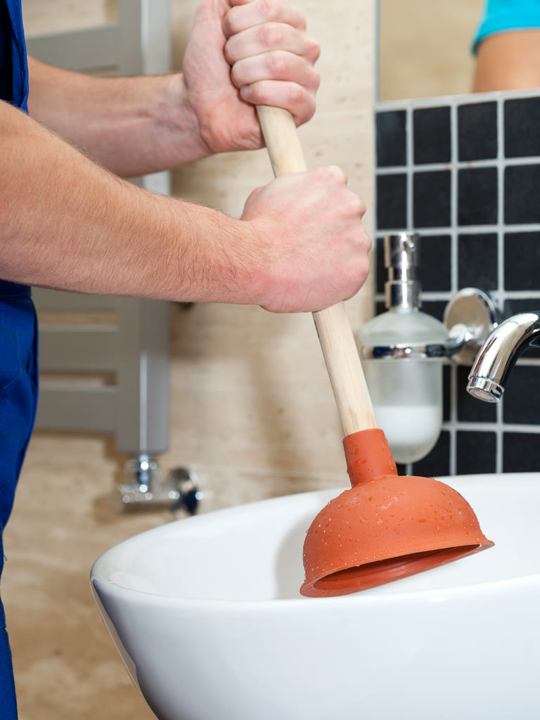 Service plumber clearing a drain line with an auger